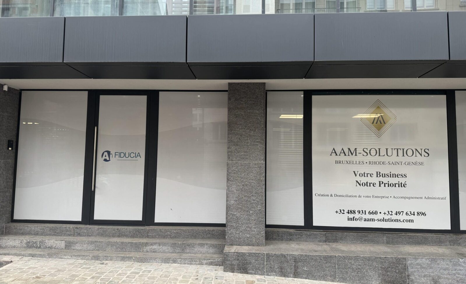 Entrée du bureau AAM-Solutions avec la vitrine affichant le logo et les informations de contact AAM-Solutions Domiciliation d'entreprises Bruxelles